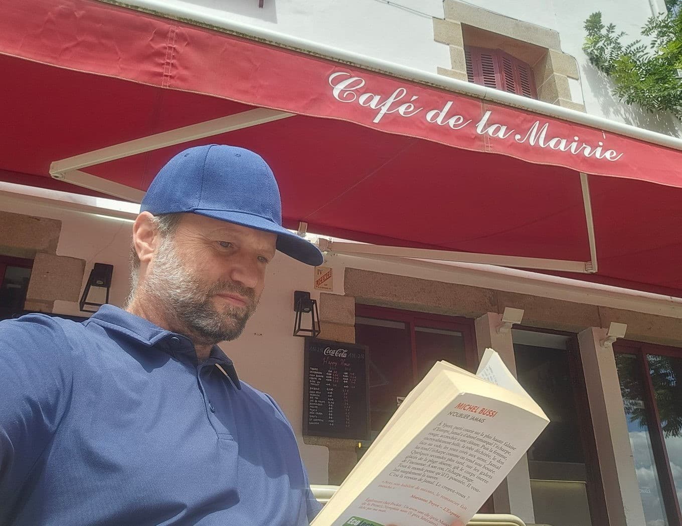 Eric Meade lisant un roman en terrasse au Café de la Mairie, au Croisic